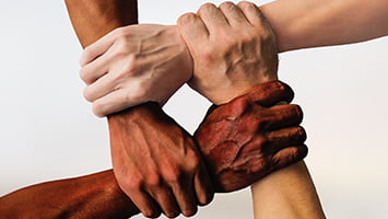 4 mains de couleur de peau différentes se tiennent conjointement le poignet.